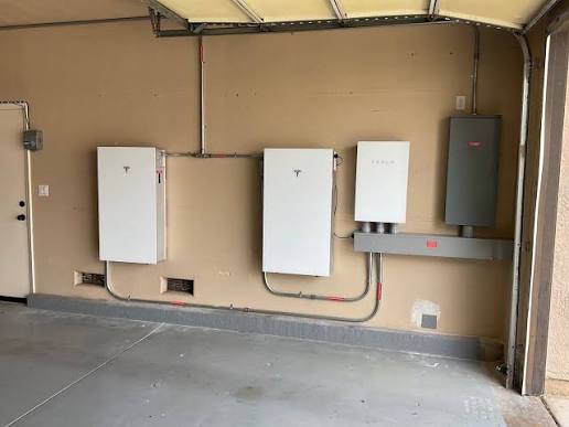 Garage wall with Tesla Powerwall units and electrical panel installed with clean conduit runs