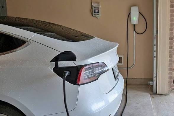 White Tesla Model 3 charging from a wall-mounted Tesla Wall Connector in a Phoenix home garage