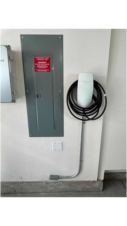 Tesla Wall Connector mounted beside a 200A electrical panel with conduit, Phoenix home